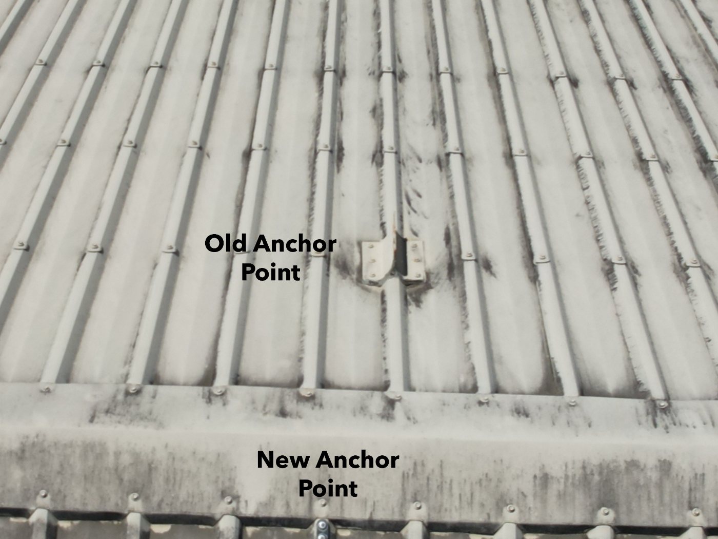 Metal roof sheeting from above with an old anchor point and a new anchor point labelled on the frame